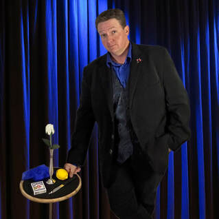 Jeff Jenson Las Vegas magician standing next to table with props on it
